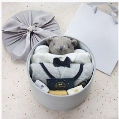 a teddy bear sitting in a gift box with clothes and a bow tie on it