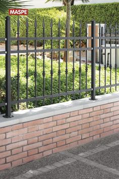 a brick wall with a black iron fence on it and a sign that reads maspe