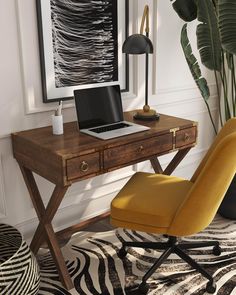 a desk with a laptop on it and a chair next to it in front of a window