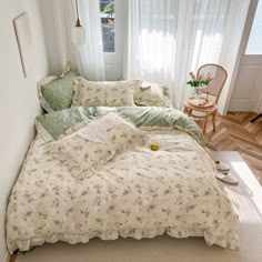 the bed is made up with green and white comforters, pillows, and blankets