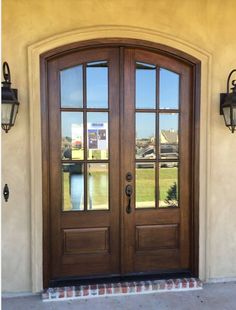 a large wooden door with two sidelights on the front of a house next to a brick walkway