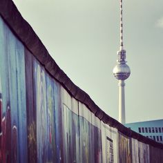 a wall with graffiti on it and a television tower in the background