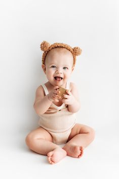 a baby is sitting on the floor and holding a piece of food in it's mouth