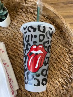 a cup with the rolling stones on it sitting on a wicker tray next to a plant