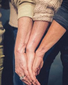 two people holding hands with small stars on their fingers and the words little tattoos below them