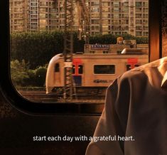 a man is looking out the window at a train passing by in front of him