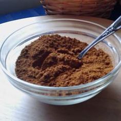 a glass bowl filled with brown powder next to a wicker basket and wooden spoon