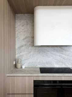 an oven and counter in a kitchen with marbled backsplash, wood paneling on the wall