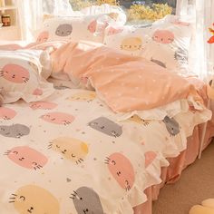 a bed covered in pink and white sheets with cats on them