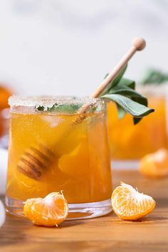 a close up of a drink on a table with oranges and leaves around it