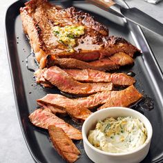 steak and mashed potatoes are served on a black plate with silverware next to it