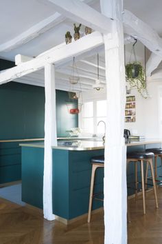 an open kitchen and dining area with bar stools in the foreground, green painted cabinets on the far wall