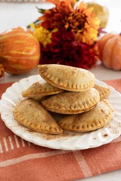 a white plate topped with three empanadas on top of a red and orange table cloth