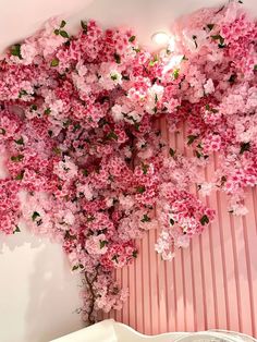 pink flowers are growing on the wall above a bed in a room with striped walls