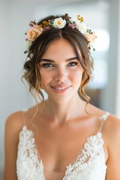 a woman with flowers in her hair wearing a wedding dress and smiling at the camera