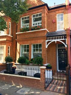 a brick house with white trim and flowers in the window boxes