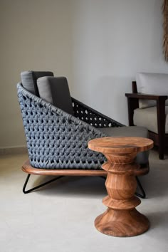 a chair and ottoman in a living room with white tile flooring next to a wooden table