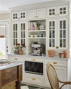 a kitchen with white cabinets and gold trim on the glass front doors, along with an oven