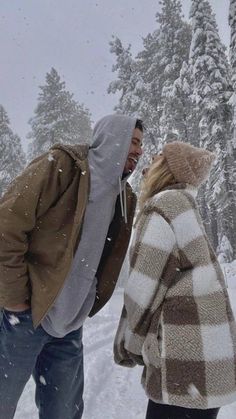 two people standing in the snow talking on their cell phones