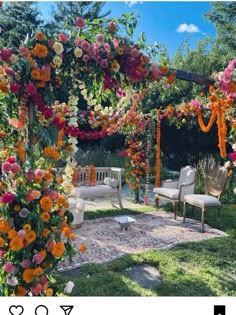 an outdoor ceremony with flowers on the arbor and chairs in the grass under it, surrounded by greenery