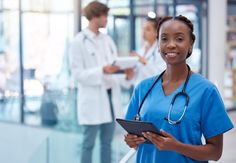 a woman in scrubs is holding a tablet