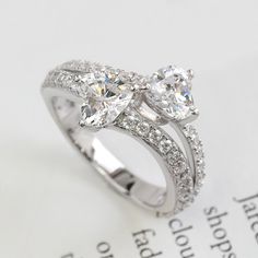 two heart shaped diamond rings on top of an open book