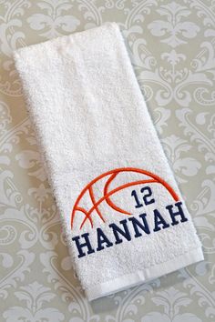 a white towel with an orange and blue basketball on it sitting on a table next to a wall