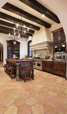 a large kitchen with an island in the center and wooden cabinets on both sides, surrounded by stone flooring