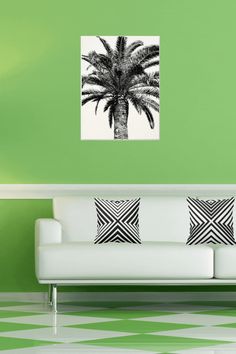 a living room with green walls and a white couch in front of a palm tree