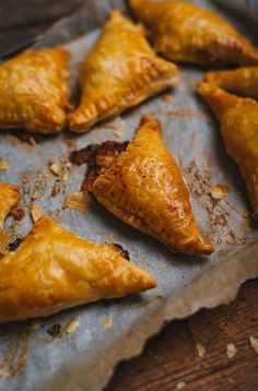 some pastries are sitting on a piece of wax paper and ready to be eaten