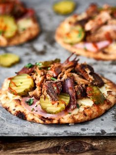 several small pizzas with meat and vegetables on them