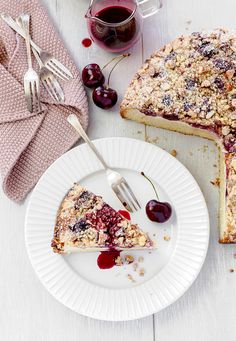 a piece of pie on a plate next to a fork and cup of coffee with cherries