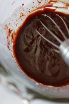 a whisk in a glass bowl filled with melted chocolate and caramel sauce