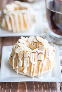 a white plate topped with a bundt cake covered in frosting and almonds