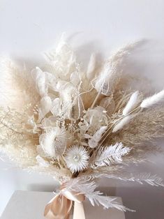 an arrangement of dried flowers and feathers in a vase