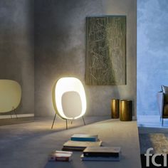 a white chair sitting on top of a floor next to a table with books and magazines