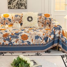 a living room with a couch covered in a blanket and flowers on the coffee table