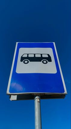 a blue and white street sign with a bus on it's left side in front of a clear blue sky