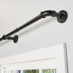 a black pipe is attached to the wall above a mirror in a room with white walls