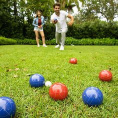 two people are playing with balls in the grass