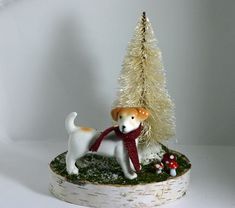 a dog figurine is standing in front of a small christmas tree and mushrooms