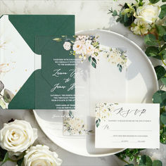 the wedding stationery is laid out on a plate with flowers and greenery around it