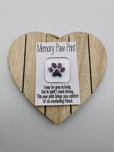 a wooden heart shaped plaque with a dog's paw print on it