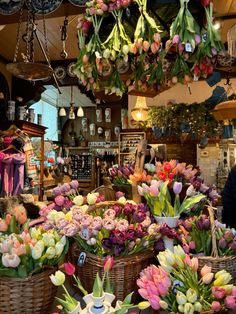 several baskets filled with flowers in front of a store display case and hanging from the ceiling