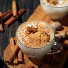 two mugs filled with cinnamon spice on top of a wooden cutting board next to cinnamon sticks