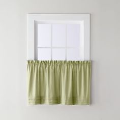 a window with a green curtain hanging from it's side in front of a white wall