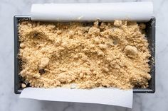 a baking pan filled with crumbs on top of a marble countertop next to a roll of paper