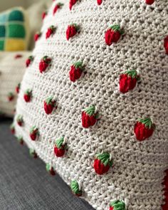 a crocheted pillow with red strawberries on it