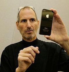 two men standing next to each other holding up their cell phones in front of them