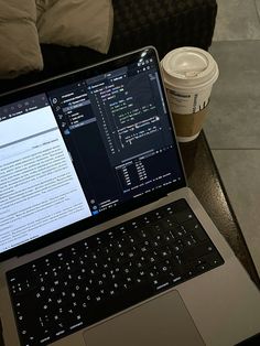 an open laptop computer sitting on top of a table next to a cup of coffee